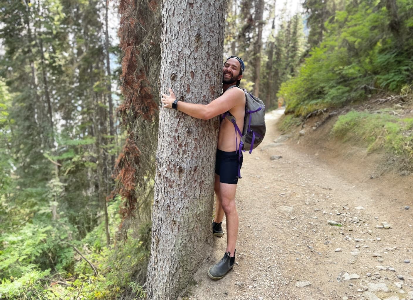 Man hugging tree wearing eco friendly ALPHX boxer brief in midnight black